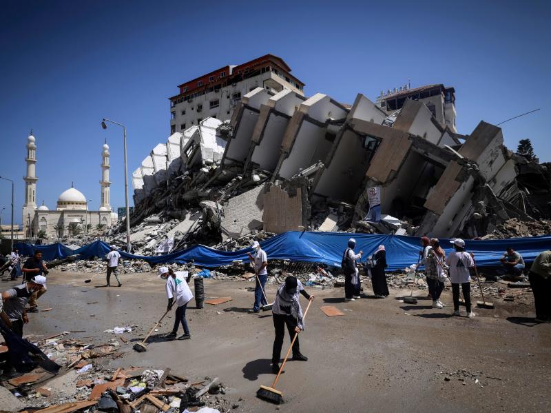 Palestinian volunteers and municipal workers clear the rubble of the Hanadi compound, recently destroyed by Israeli strikes, in Gaza City's Rimal district, on May 25, 2021. Palestinian volunteers and municipal workers clear the rubble of the Hanadi compound, recently destroyed by Israeli strikes, in Gaza City's Rimal district, on May 25, 2021.