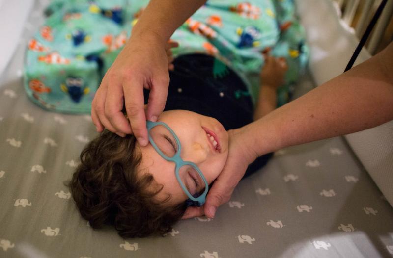 Kathleen helps her son Gideon get his glasses on. Part of Gideon's brain was damaged during development, which effects his vision. Kathleen helps her son Gideon get his glasses on. Part of Gideon's brain was damaged during development, which effects his vision.