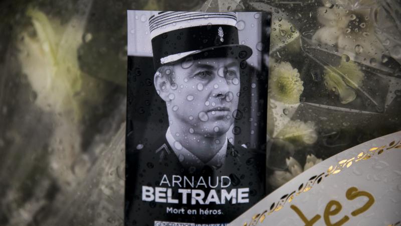 A photo of Lt. Col. Arnaud Beltrame rests on a bunch of flowers at the main gate of the police headquarters in Carcassonne, France. On Sunday, a man was arrested on charges of apologizing for terrorism after seemingly praising Beltrame's death on social m A photo of Lt. Col. Arnaud Beltrame rests on a bunch of flowers at the main gate of the police headquarters in Carcassonne, France. On Sunday, a man was arrested on charges of apologizing for terrorism after seemingly praising Beltrame's death on social m