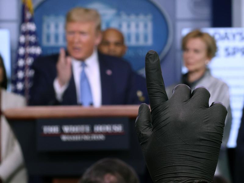 A reporter wearing a latex glove raises his hand to ask President Trump a question during a coronavirus briefing at the White House on March 16. A reporter wearing a latex glove raises his hand to ask President Trump a question during a coronavirus briefing at the White House on March 16.
