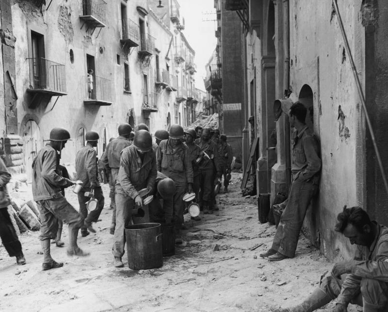 American GIs line up in the street in Troina, Sicily, utensils and dishes in hand, as they wait for a meal from a large pot, July 1943. Oregano grows abundantly in Southern Italy, where many GIs encountered the herb for the first time, and fell in love. M American GIs line up in the street in Troina, Sicily, utensils and dishes in hand, as they wait for a meal from a large pot, July 1943. Oregano grows abundantly in Southern Italy, where many GIs encountered the herb for the first time, and fell in love. M