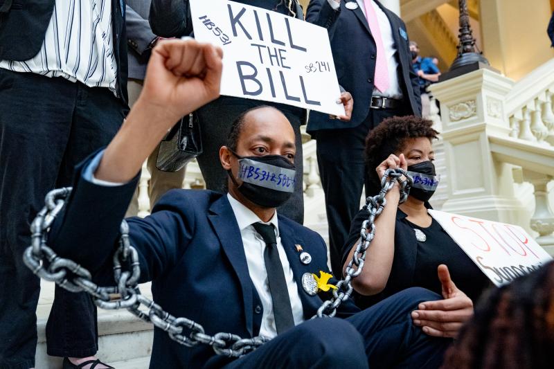 Demonstrators who oppose voting bills that, among other things, would end no-excuse absentee voting, wear chains while holding a sit-in inside the Georgia Capitol in Atlanta on Monday. Demonstrators who oppose voting bills that, among other things, would end no-excuse absentee voting, wear chains while holding a sit-in inside the Georgia Capitol in Atlanta on Monday.