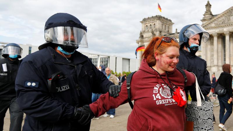 German police detain a demonstrator during a protest against the government's restrictions to prevent the spread of the coronavirus in front of the Reichstag in Berlin on Saturday. German police detain a demonstrator during a protest against the government's restrictions to prevent the spread of the coronavirus in front of the Reichstag in Berlin on Saturday.