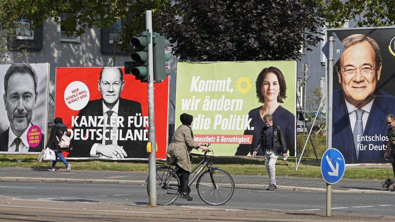 On Thursday, people in Gelsenkirchen, Germany, pass election posters of chancellor candidates Armin Laschet (from right) of the Christian Democratic Union, Annalena Baerbock of the Greens, Olaf Scholz of the Social Democratic Party and Christian Lindner o On Thursday, people in Gelsenkirchen, Germany, pass election posters of chancellor candidates Armin Laschet (from right) of the Christian Democratic Union, Annalena Baerbock of the Greens, Olaf Scholz of the Social Democratic Party and Christian Lindner o