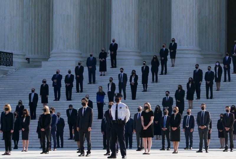 Former law clerks for Justice Ruth Bader Ginsburg stand on the steps of the U.S. Supreme Court in Washington, D.C., as they await the arrival of the casket on Wednesday. Former law clerks for Justice Ruth Bader Ginsburg stand on the steps of the U.S. Supreme Court in Washington, D.C., as they await the arrival of the casket on Wednesday.