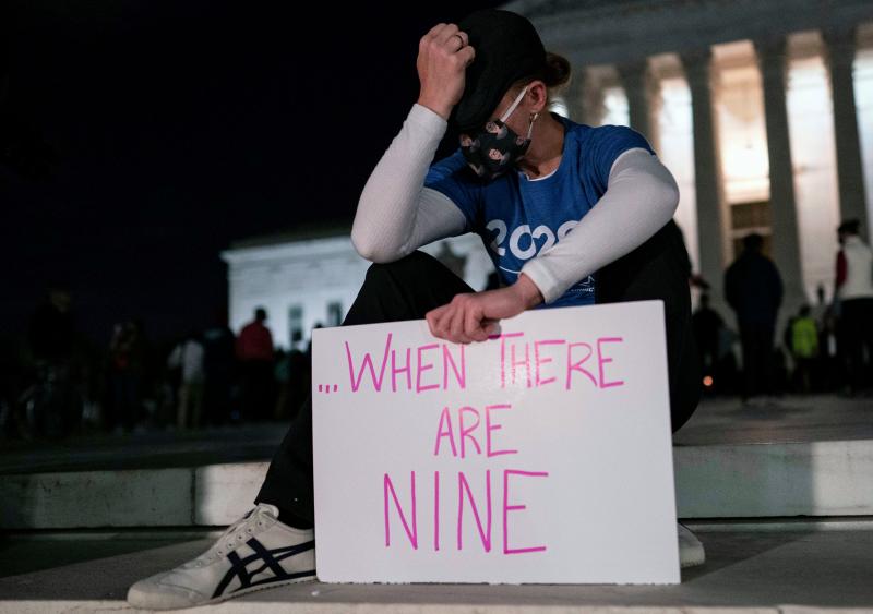 A woman, mourning the death of Ruth Bader Ginsburg, holds a sign at the Supreme Court that reads, "when there are nine," something Ginsburg said to describe when there'd be enough women on the court. A woman, mourning the death of Ruth Bader Ginsburg, holds a sign at the Supreme Court that reads, "when there are nine," something Ginsburg said to describe when there'd be enough women on the court.