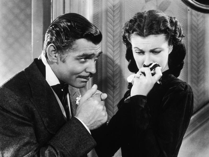 American actor Clark Gable in his role as Rhett Butler kissing the hand of a tearful Scarlett O'Hara, played by Vivien Leigh in 'Gone With The Wind'. American actor Clark Gable in his role as Rhett Butler kissing the hand of a tearful Scarlett O'Hara, played by Vivien Leigh in 'Gone With The Wind'.