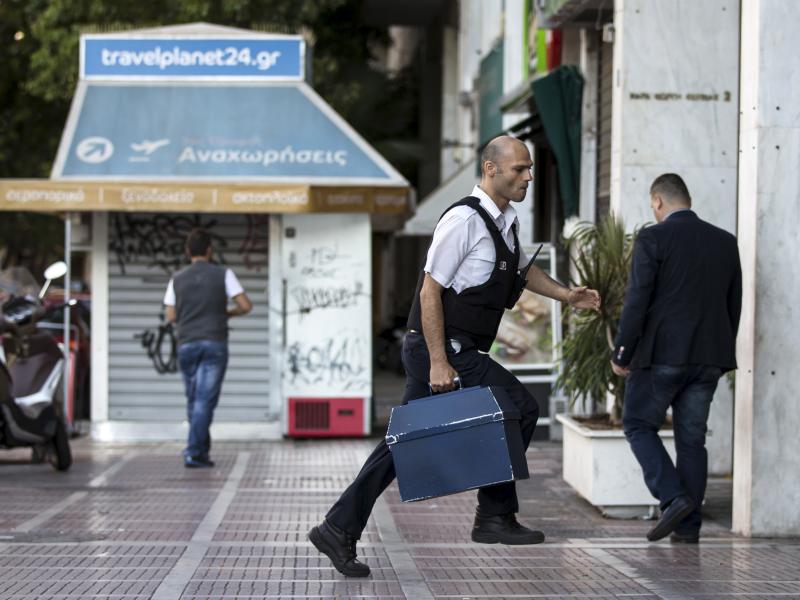 A security worker brings money to a National Bank branch in Athens on Sunday. Greeks have been withdrawing euros in anticipation of a possible default on the country's debt payments early next week. A security worker brings money to a National Bank branch in Athens on Sunday. Greeks have been withdrawing euros in anticipation of a possible default on the country's debt payments early next week.