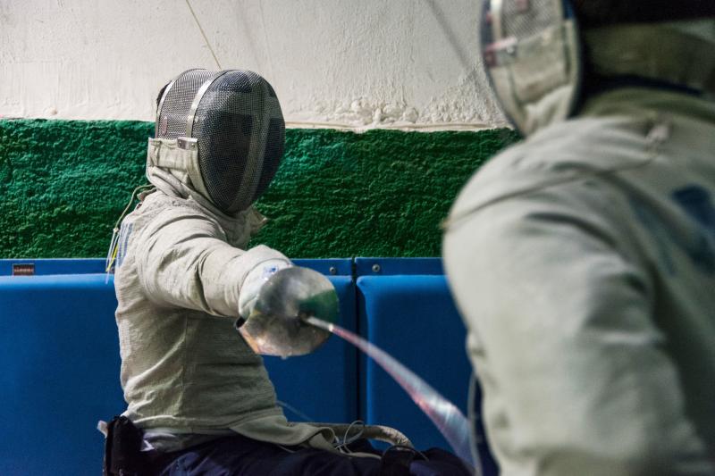 Panos Triantafyllou (left), in his fencing uniform and mask, trains with Vasilis Ntounis, his fellow Paralympic athlete and close friend. Panos Triantafyllou (left), in his fencing uniform and mask, trains with Vasilis Ntounis, his fellow Paralympic athlete and close friend.