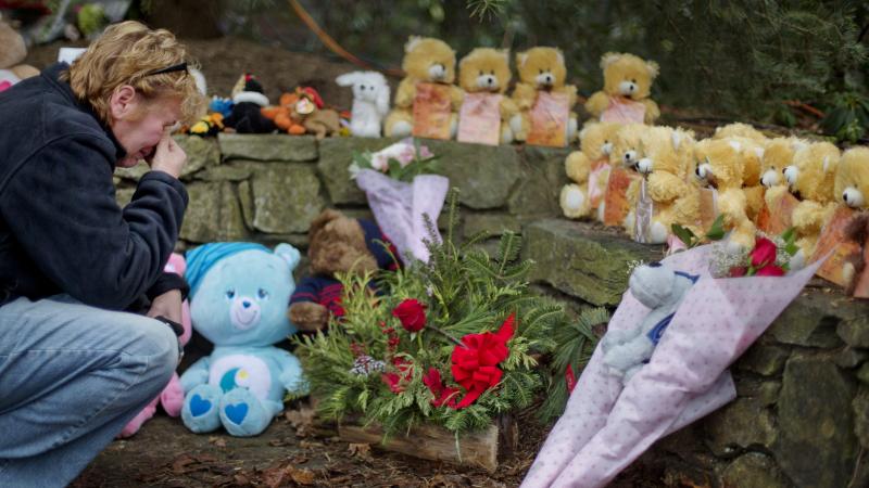 A mourner kneels beside 26 teddy bears, each representing a victim of the Sandy Hook Elementary School shooting, at a sidewalk memorial in 2012 in Newtown, Conn. A mourner kneels beside 26 teddy bears, each representing a victim of the Sandy Hook Elementary School shooting, at a sidewalk memorial in 2012 in Newtown, Conn.