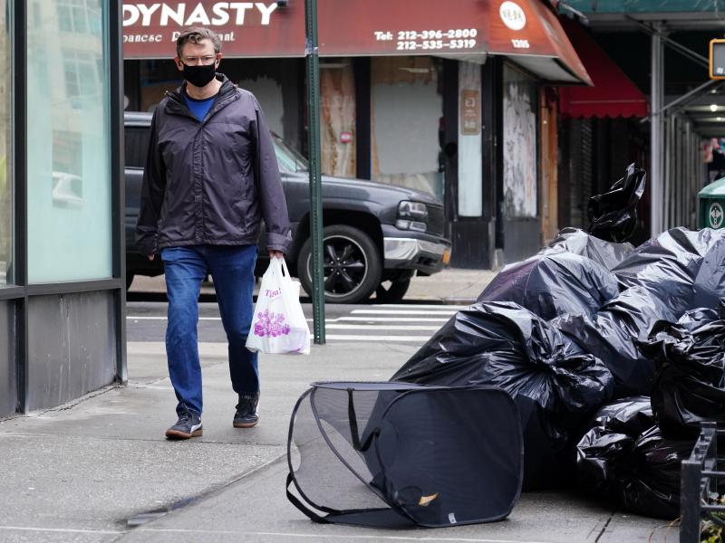 A man wearing a protective mask looks at piled-up trash in New York City on April 24. Cities are struggling with collection as the volume of residential garbage surges during the stay-at-home era. A man wearing a protective mask looks at piled-up trash in New York City on April 24. Cities are struggling with collection as the volume of residential garbage surges during the stay-at-home era.