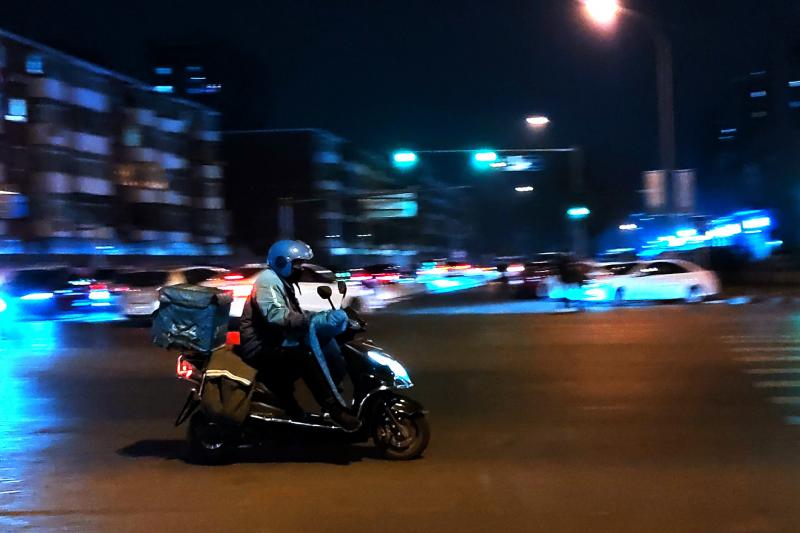 A courier delivers goods at night on a street in Beijing in February. A courier delivers goods at night on a street in Beijing in February.