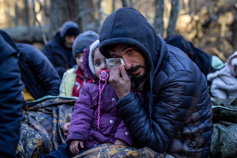 A man holding a child wipes his eye as the Kurdish family from Dohuk in Iraq waits for the border guard patrol, near Narewka, Poland, near the Polish-Belarusian border on Nov. 9. The three-generation family of 16 — with seven minors, including the young A man holding a child wipes his eye as the Kurdish family from Dohuk in Iraq waits for the border guard patrol, near Narewka, Poland, near the Polish-Belarusian border on Nov. 9. The three-generation family of 16 — with seven minors, including the young