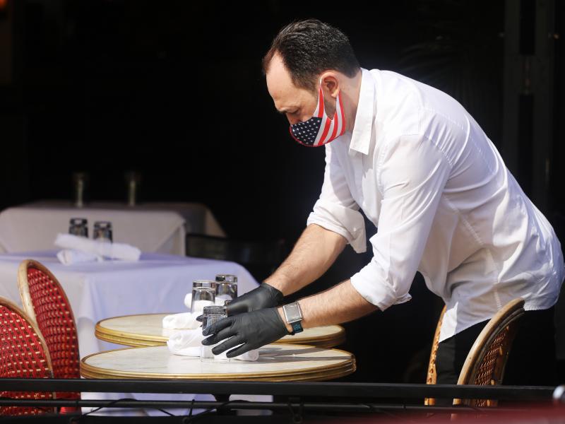 A restaurant server in New York prepares a table. But people remain cautious about going out and spending money. A restaurant server in New York prepares a table. But people remain cautious about going out and spending money.