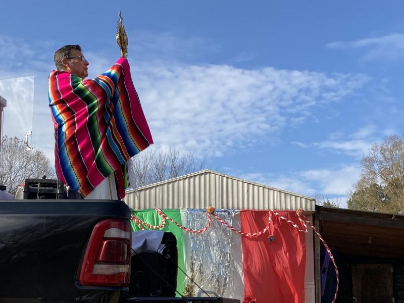Father Julio Martinez raises the Blessed Sacrament from the back of a pickup truck in Ramseur, N.C. Father Julio Martinez raises the Blessed Sacrament from the back of a pickup truck in Ramseur, N.C.