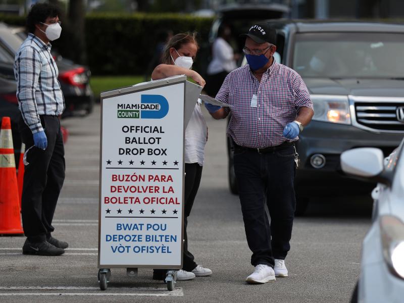 Poll workers at the Miami-Dade County Elections Department deposit returned mail-in ballots into an official ballot drop box on primary election day on Aug. 18 in Doral, Fla. Poll workers at the Miami-Dade County Elections Department deposit returned mail-in ballots into an official ballot drop box on primary election day on Aug. 18 in Doral, Fla.