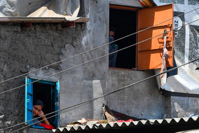 Residents look out of their windows at the Dharavi slum during a government-imposed nationwide lockdown. Residents look out of their windows at the Dharavi slum during a government-imposed nationwide lockdown.