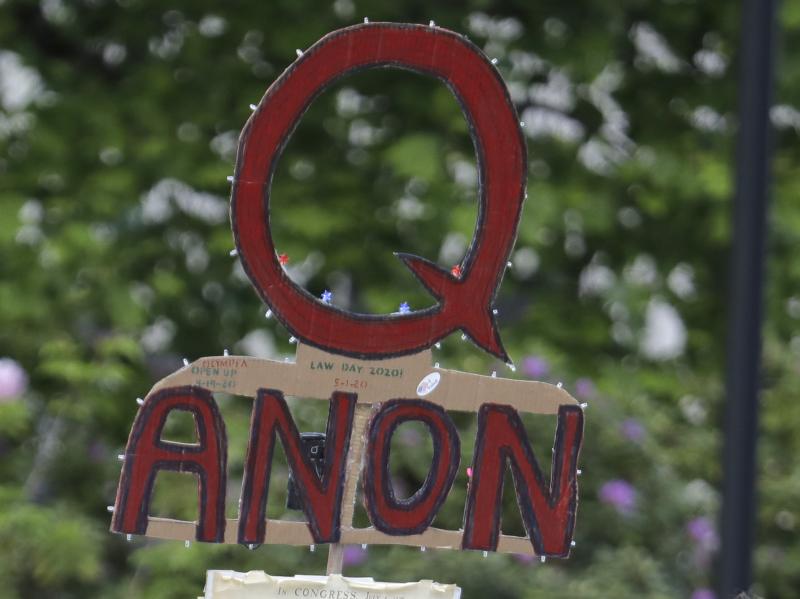 A person carries a sign supporting QAnon during a May 2020 protest rally in Olympia, Wash. A person carries a sign supporting QAnon during a May 2020 protest rally in Olympia, Wash.