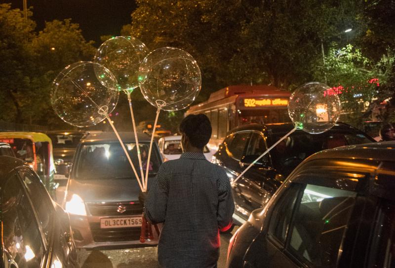 Radhesham Singh, a homeless 28-year-old street vendor in New Delhi, saunters amid traffic, selling balloons. Radhesham Singh, a homeless 28-year-old street vendor in New Delhi, saunters amid traffic, selling balloons.