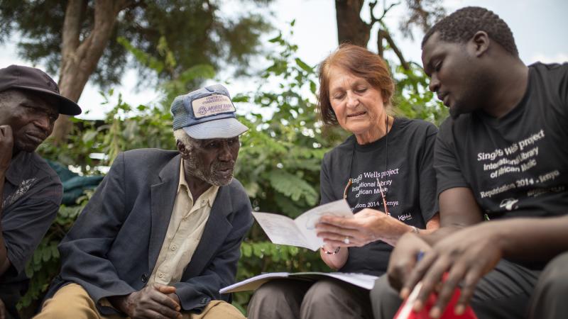 Philip Cheruiyot (second from left) leans in to read the song titles on the CD booklet brought by Diane Thram. Cheruiyot's grandfather sang on Hugh Tracey's recording of "Chemirocha II." Philip Cheruiyot (second from left) leans in to read the song titles on the CD booklet brought by Diane Thram. Cheruiyot's grandfather sang on Hugh Tracey's recording of "Chemirocha II."