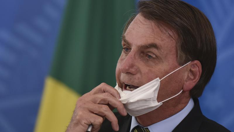 Brazil's President Jair Bolsonaro removes his mask to speak to journalists after a press conference on the coronavirus on Wednesday. Brazil's President Jair Bolsonaro removes his mask to speak to journalists after a press conference on the coronavirus on Wednesday.