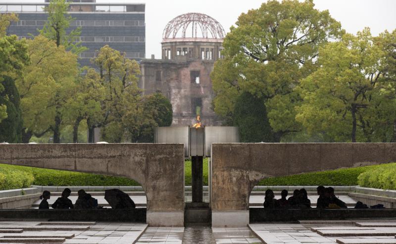 Visitors shelter from the rain under the Peace Flame as they visit the Memorial Park and the nearby Hiroshima Peace Memorial Museum on April 21 in Hiroshima, Japan. The dome in the background was destroyed during the attack, and preserved as a monument. T Visitors shelter from the rain under the Peace Flame as they visit the Memorial Park and the nearby Hiroshima Peace Memorial Museum on April 21 in Hiroshima, Japan. The dome in the background was destroyed during the attack, and preserved as a monument. T