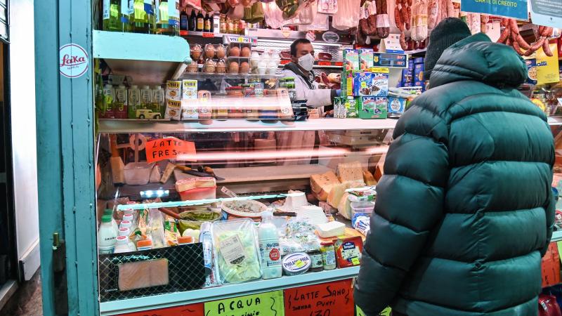 A vendor wearing protective masks and gloves serves a customer at a market in Rome on April 16. A vendor wearing protective masks and gloves serves a customer at a market in Rome on April 16.