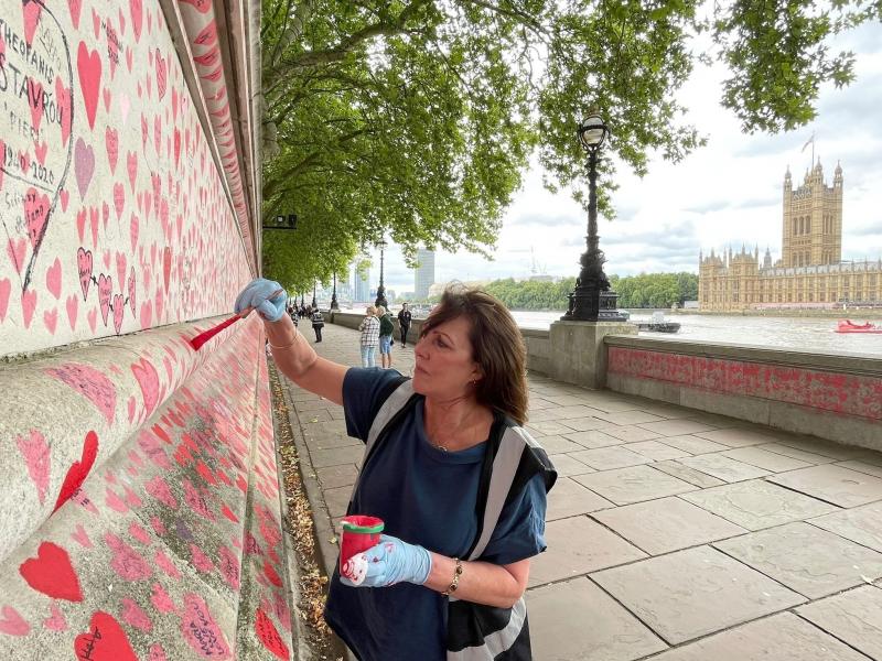 Fran Hall paints hearts on a memorial in London dedicated to people who have died from COVID-19. She and other activists are pushing for the British government to investigate its handling of the pandemic. Fran Hall paints hearts on a memorial in London dedicated to people who have died from COVID-19. She and other activists are pushing for the British government to investigate its handling of the pandemic.