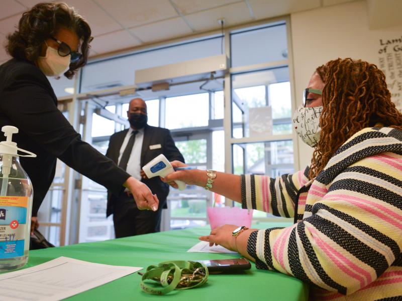 Yvette Richards, director of community connection at St. James United Methodist Church in Kansas City, Mo., checks temperatures before Sunday morning services. The church is hosting vaccination clinics and holding socially distanced services after shuttin Yvette Richards, director of community connection at St. James United Methodist Church in Kansas City, Mo., checks temperatures before Sunday morning services. The church is hosting vaccination clinics and holding socially distanced services after shuttin