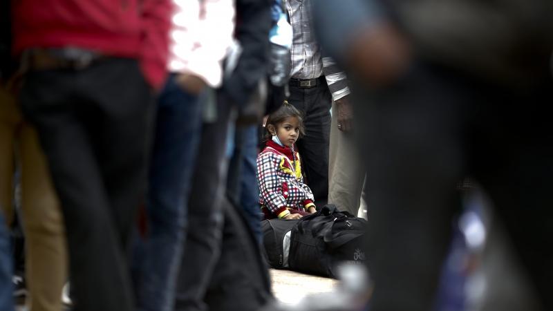 A young girl sits on her luggage as she waits in a long line with her family, hoping to board buses provided by the government to return to their homes outside Kathmandu. A young girl sits on her luggage as she waits in a long line with her family, hoping to board buses provided by the government to return to their homes outside Kathmandu.