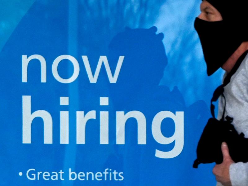 A man wearing a face mask walks past a "Now Hiring" sign in front of a store on Jan. 13, in Arlington, Va. The labor market is showing resilience despite a recent spike in omicron-related coronavirus infections. A man wearing a face mask walks past a "Now Hiring" sign in front of a store on Jan. 13, in Arlington, Va. The labor market is showing resilience despite a recent spike in omicron-related coronavirus infections.