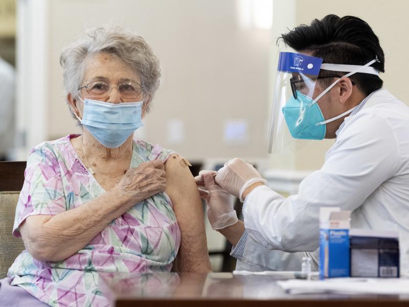 A CVS pharmacist gives the Pfizer/BioNTech COVID-19 vaccine to a resident at the Emerald Court senior living community in Anaheim, Calif., in January. Federal health officials have revised advice on nursing home visitations for the first time since Septem A CVS pharmacist gives the Pfizer/BioNTech COVID-19 vaccine to a resident at the Emerald Court senior living community in Anaheim, Calif., in January. Federal health officials have revised advice on nursing home visitations for the first time since Septem