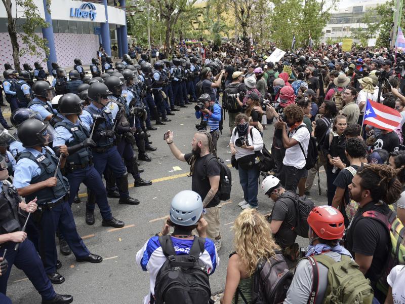 Police form a barrier against protesters during a May Day march Tuesday in San Juan, Puerto Rico, to protest pension cuts, school closures and slow hurricane recovery efforts. Police form a barrier against protesters during a May Day march Tuesday in San Juan, Puerto Rico, to protest pension cuts, school closures and slow hurricane recovery efforts.