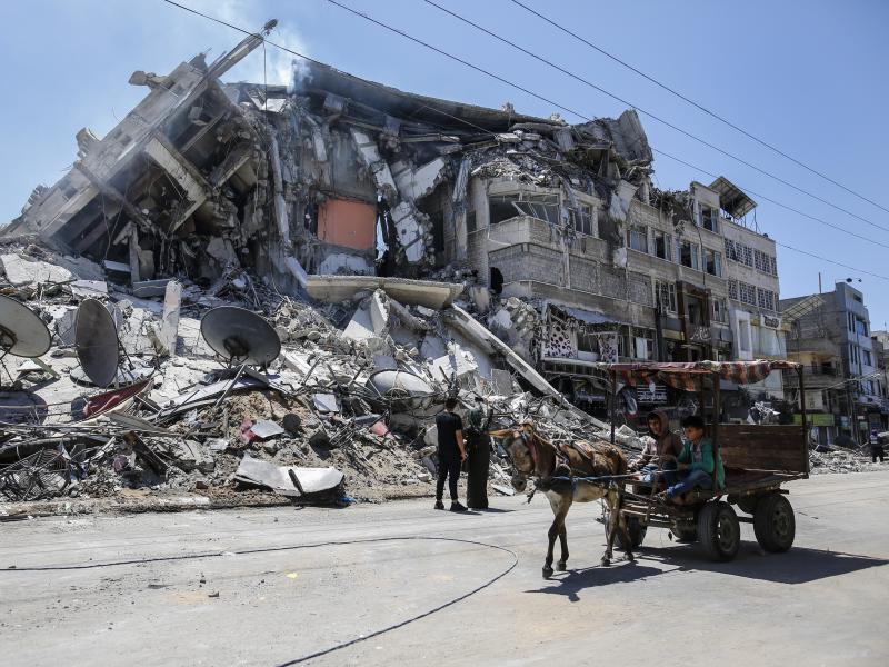 Palestinians walk past the debris of the Al-Sharouk tower in Gaza City, which collapsed after being hit by an Israeli air strike. Palestinians walk past the debris of the Al-Sharouk tower in Gaza City, which collapsed after being hit by an Israeli air strike.