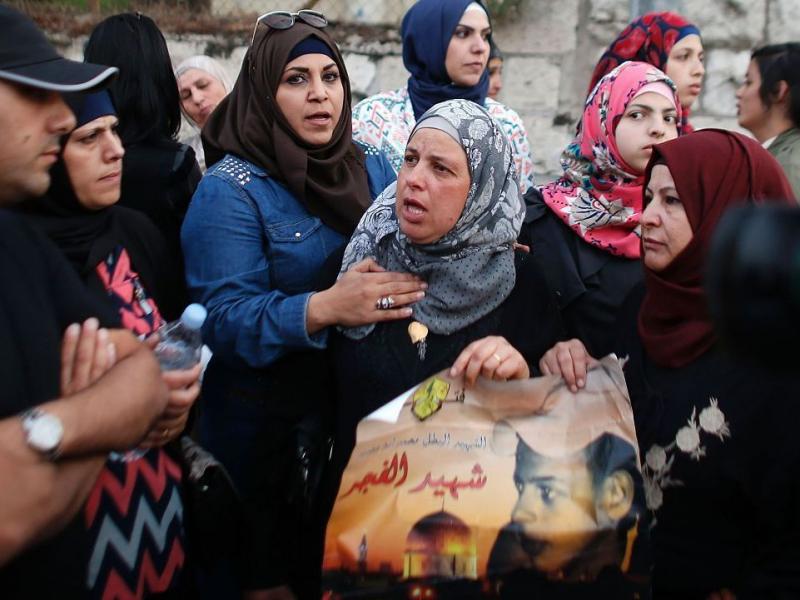Suha (center), the mother of murdered Palestinian teenager Mohammed Abu Khdeir, takes part in a protest outside the district court in Jerusalem on Tuesday. She's holding a picture of her son. Suha (center), the mother of murdered Palestinian teenager Mohammed Abu Khdeir, takes part in a protest outside the district court in Jerusalem on Tuesday. She's holding a picture of her son.