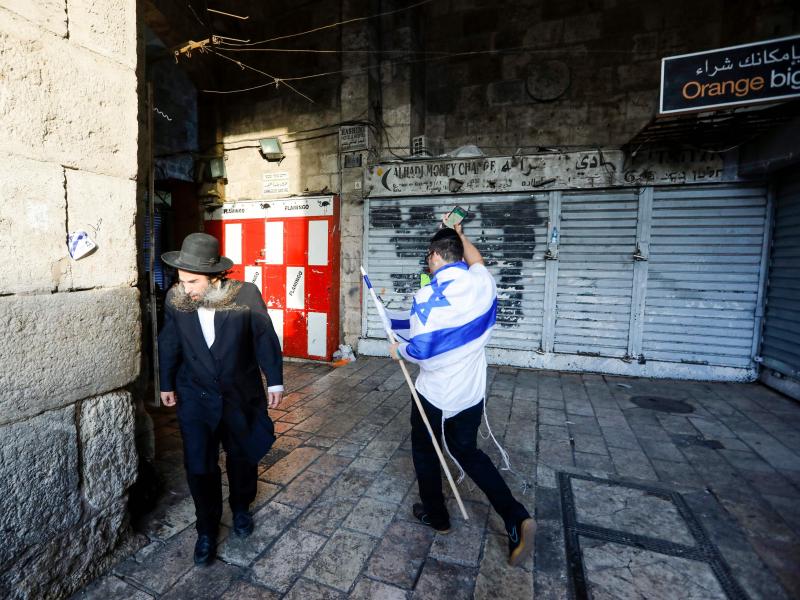 An Israeli draped in the national flag walks past an ultra-Orthodox Jewish man in Jerusalem's Old City on May 13, as Israelis marked Jerusalem Day. An Israeli draped in the national flag walks past an ultra-Orthodox Jewish man in Jerusalem's Old City on May 13, as Israelis marked Jerusalem Day.
