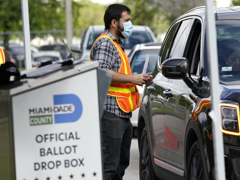 An election worker takes ballots from voters dropping them off at an official ballot drop box this week at the Miami-Dade County Board of Elections in Doral, Fla. An election worker takes ballots from voters dropping them off at an official ballot drop box this week at the Miami-Dade County Board of Elections in Doral, Fla.