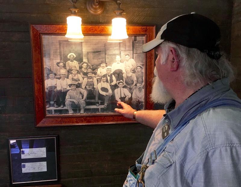 Tour guide Ron Craig points to a photo in Jack Daniel's old office at the whiskey maker's distillery in Lynchburg, Tenn. The photo, taken in the 1890s, shows Jack Daniel (wearing a black-banded white hat and a gray goatee), seated next to an African-Ameri Tour guide Ron Craig points to a photo in Jack Daniel's old office at the whiskey maker's distillery in Lynchburg, Tenn. The photo, taken in the 1890s, shows Jack Daniel (wearing a black-banded white hat and a gray goatee), seated next to an African-Ameri