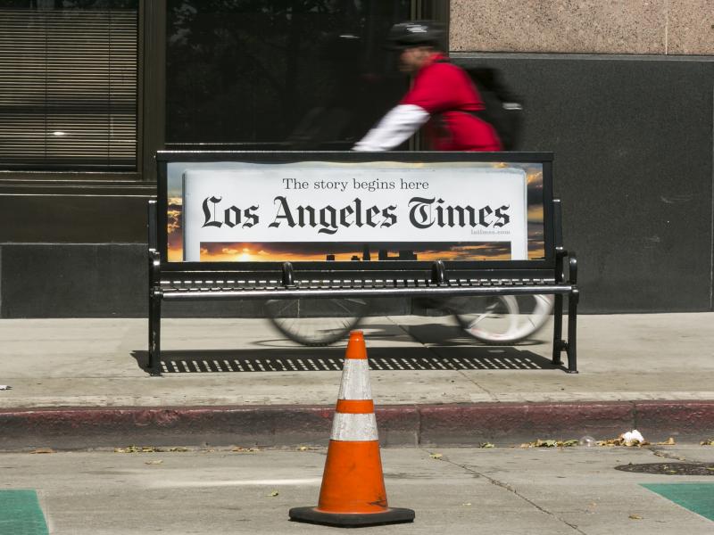A cyclist rides on the sidewalk past a Los Angeles Times advertisement in downtown Los Angeles. The newspaper is being sued by employees alleging pay discrimination. A cyclist rides on the sidewalk past a Los Angeles Times advertisement in downtown Los Angeles. The newspaper is being sued by employees alleging pay discrimination.