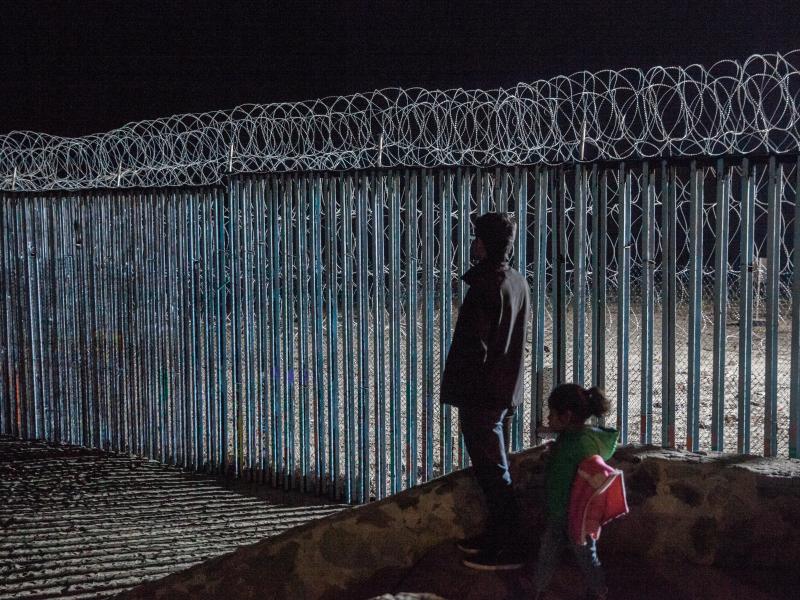 A young man and a little girl look at the border fence from Playas de Tijuana, Mexico. Photojournalist Ariana Drehsler has been covering the caravan of migrants for weeks. In December, Customs and Border Protection agents began pulling her over for questi A young man and a little girl look at the border fence from Playas de Tijuana, Mexico. Photojournalist Ariana Drehsler has been covering the caravan of migrants for weeks. In December, Customs and Border Protection agents began pulling her over for questi