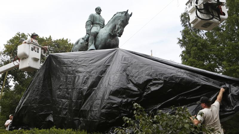 City workers drape a tarp over the statue of Confederate General Robert E. Lee in Charlottesville, Va. on Aug. 23, 2017. City workers drape a tarp over the statue of Confederate General Robert E. Lee in Charlottesville, Va. on Aug. 23, 2017.