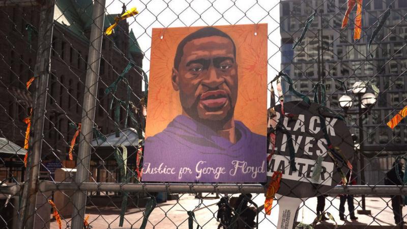 A picture of George Floyd hangs on a fence barrier that surrounds the Hennepin County Government Center in Minneapolis during the trial of former police officer Derek Chauvin in March. The Justice Department is now bringing criminal charges against Chauvi A picture of George Floyd hangs on a fence barrier that surrounds the Hennepin County Government Center in Minneapolis during the trial of former police officer Derek Chauvin in March. The Justice Department is now bringing criminal charges against Chauvi
