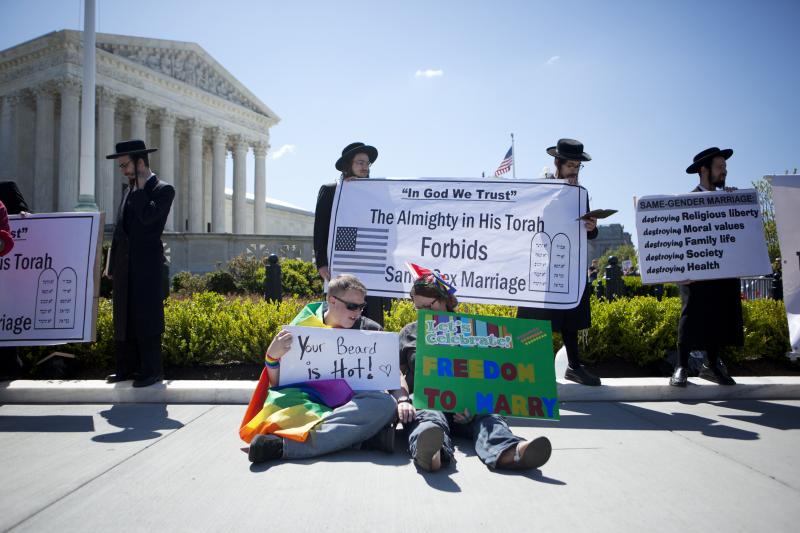 Michelle McKelvey (left) and Meg McKelvey sit near demonstrators outside of the Supreme Court on Tuesday. They have been together for two years. Michelle McKelvey (left) and Meg McKelvey sit near demonstrators outside of the Supreme Court on Tuesday. They have been together for two years.
