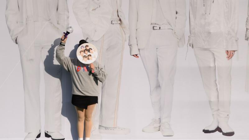 A fan of K-pop band BTS poses for photos against a backdrop featuring an image of the group's members in Seoul, South Korea, on Oct. 29, 2019. A fan of K-pop band BTS poses for photos against a backdrop featuring an image of the group's members in Seoul, South Korea, on Oct. 29, 2019.