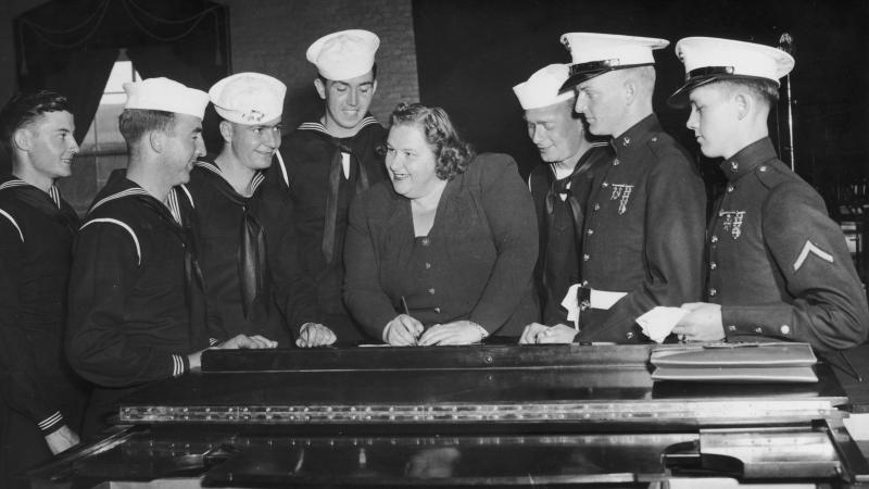 Singer Kate Smith signs autographs for a group of American sailors circa 1938. Singer Kate Smith signs autographs for a group of American sailors circa 1938.