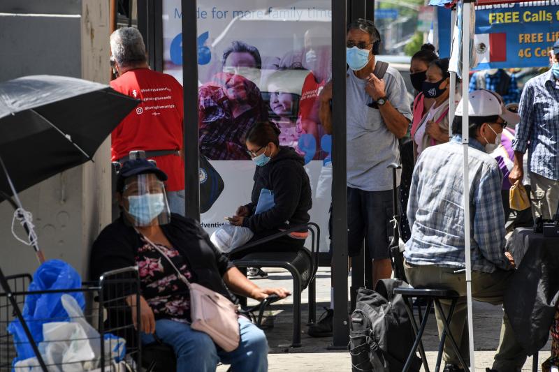 People wait for a bus in August in East Los Angeles. Latinos have the highest rate of labor force participation of any group in California — many in public-facing jobs deemed essential. That work has put them at higher risk of catching the coronavirus. People wait for a bus in August in East Los Angeles. Latinos have the highest rate of labor force participation of any group in California — many in public-facing jobs deemed essential. That work has put them at higher risk of catching the coronavirus.