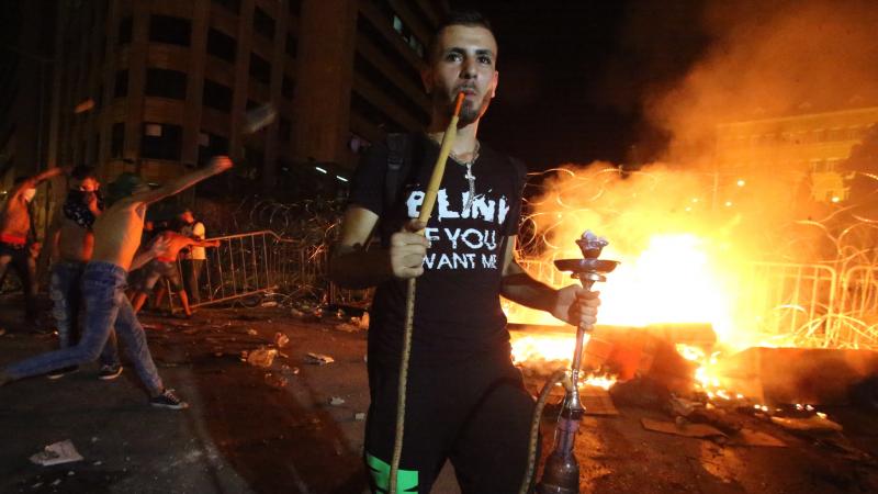 A Lebanese protester smokes a water pipe during clashes with security forces following a demonstration against the ongoing trash crisis Tuesday. A Lebanese protester smokes a water pipe during clashes with security forces following a demonstration against the ongoing trash crisis Tuesday.