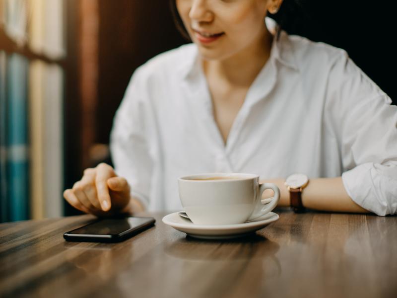 A young woman sits in cafe while text messaging on her smartphone. A young woman sits in cafe while text messaging on her smartphone.