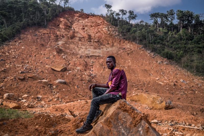 Samuel Senessie, 25, at the site of last year's mudslide. He lost five members of his family and his home. He says he has not received the government support to which he should be entitled. Samuel Senessie, 25, at the site of last year's mudslide. He lost five members of his family and his home. He says he has not received the government support to which he should be entitled.
