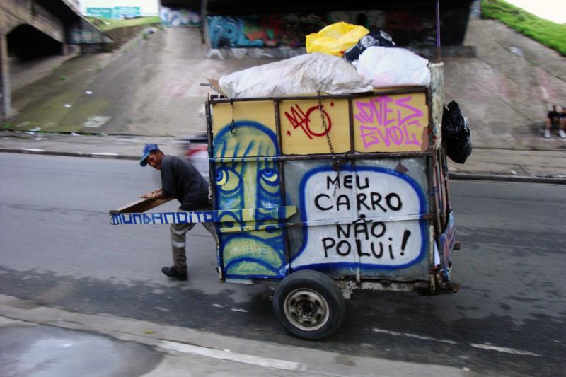 A waste picker wheels a trash cart with Mundano's art and spreads the word: "My cart doesn't pollute." A waste picker wheels a trash cart with Mundano's art and spreads the word: "My cart doesn't pollute."
